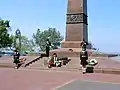 Male and female cadets bowing their heads in respect while guarding the monument.