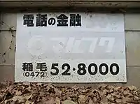 古いタイプの看板。稲毛（千葉市）の市外局番が0472であることから、1992年以前に設置されたものであることがうかがえる。