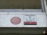 昭和に建てられた建物の、正面入り口にある金属製ドア枠に貼られた明治33年の建物財産票