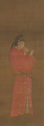 Portrait of a woman in disguise of a man wearing a red round-necked robe of the nobility and a cap of black gauze. A yokobue transverse flute is tucked in her obi and she is watchpg=PA159ing the fingers of both of her hands.