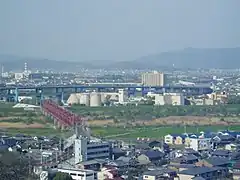 鋼索線車内からの景色。京阪本線の赤いトラス橋が架かる木津川、その向こう側に京滋バイパスの高架橋と宇治川、さらにその向こう側には京都競馬場と横大路運動公園が見える。