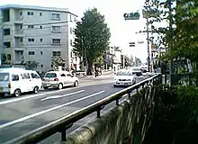 喜平橋杉並方面から玉川上水の北に沿って来た五日市街道は、ここでクランク状に折れ曲がって玉川上水を渡り、今度はその南に沿ってあきる野方面へ向かう。画面左で自動車2台が停止しているのがあきる野方面へ向かう右折レーン。