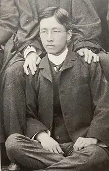 青年時代の好本督が七三分けの髪型で眼鏡をかけ、背広を着て集合写真に写り込んでいる。