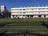 南側公道から校庭と校舎の北西を見る（2015年1月撮影）