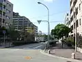 甲子園競輪場の跡地に建つ分譲マンション(左側)。道路右側歩道に写る屋根の部分が、かつて運行されていた甲子園駅ゆき無料送迎バス乗り場(屋根は撤去済み)。停車中のトラックの奥辺りが、かつての正門の位置。