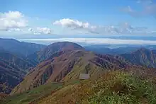 避難小屋と雲海広がる新庄盆地(左奥は月山)