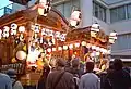 市内を練り歩く山車の上段で祭囃子を披露