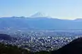 甲府市街とセインツ.25（中央やや左下）。背後に富士山。（2010年1月）