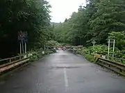 湯の沢ゲート(左、北斗市湯ノ沢)と桧木橋ゲート(右、厚沢部町字富里)。左右ゲート間は梅漬峠を経由して通年通行止めとなっている。