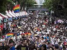 レインボーフラッグを掲げて道を埋め尽くす人々の風景