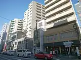 東京メトロ千代田線千駄木駅 出入口1南側至近の街並み【右から「レガシー千駄木」(1階…サンマルクカフェ)、「カトロス千駄木」、「サンウッド文京千駄木フラッツ」(1階…やなか珈琲店等)、「吉江ビル」(1階…おにぎりカフェ利さく等)】(2018年4月)