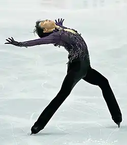 レイバック・イナバウアーをする羽生結弦の写真。両脚を縦に大きく開き、背中を反らして腕を大きく広げたまま滑走している。