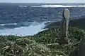 崖上の浦野墓地に立ち海を見下ろす地蔵。環境の厳しさを感じさせる。