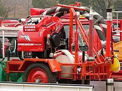 可搬消防ポンプと手引き台車を軽トラックの荷台に搭載したところ。手引き台車にも金色の装飾線あり。（菊池市消防団）