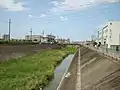 第二寝屋川萬右衛門橋より下流を望む。左岸には福万寺町市民運動広場内の調整池との合流門が見える。一番手前に見える橋は新沢橋。