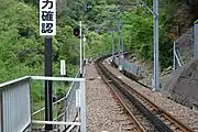 アプトいちしろ駅から井川方面を見る、長島ダム駅まで続くラックレールと奥に90 ‰(パーミル)の勾配標が見える。