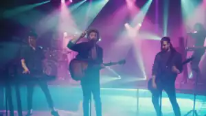The members of AJR performing. From left to right, Ryan holding a ukulele, Jack singing, and Adam holding a guitar.