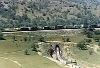 アッチソン・トピカ・アンド・サンタフェ鉄道（当時）の東行き貨物列車の先頭部が、その列車の後部の上に差し掛かる様子（1987年4月の撮影）