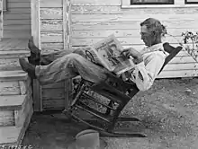 ロッキングチェアで農業新聞を読む農夫(George W. Ackerman写真。1931年、テキサス州)