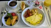 エールフランス、ビジネスクラス、朝食(2013年5月) カフェオレ(あるいはコーヒー)、パン、オムレツ、フルーツ、ヨーグルト。フランスらしくBonne Maman(ボヌ・ママン) ブランドのチェック柄の小瓶に入ったジャムがついている。