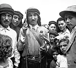 Man holding a falcon, in the centre of a group of people