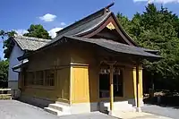 社殿拝殿（黄色い壁の部分）から続く屋根覆い（白い壁の部分）により本殿は雨風から保護されている。