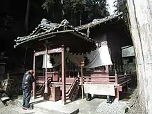 神社の拝殿の前で手を合わせる参拝者。