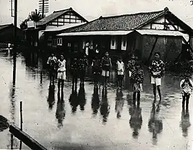 大雨で冠水した甲州街道と子供たち。現在の甲府市酒折地区の城東通り。1925年(大正14年)8月の撮影。