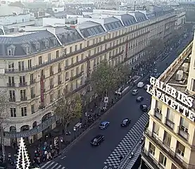 ディアギルヴ広場のギャルリー・ラファイエットから見るオスマン大通り (Le boulevard Haussmann vu depuis la terrasse des Galeries Lafayette.)。左建物はギャルリー・ラファイエットの食品館 (Lafayette Maison & Gourmet) で、オスマン大通り先にはC&Aやプランタンが連なる。