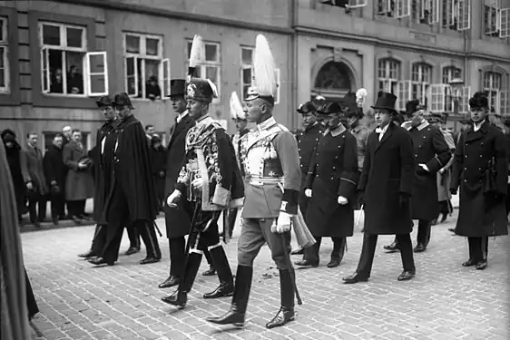 1926年、母方祖母のデンマーク王妃ルイーセ・ア・スヴェーリエ＝ノーウの葬儀に出席した際のクリスティアン（中央・灰色の軍服）。左隣はプロイセン王子ジギスムント（黒い軍服）。