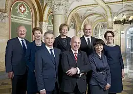 連邦参事会のメンバー7人と連邦事務総長（2012年）。左からヨハン・シュナイダー＝アマン、シモネッタ・ソマルーガ、ディディエ・ビュルカルテ、エフェリーネ・ヴィドマー＝シュルンプフ、ウエリ・マウラー、ベルセ、ドリス・ロイトハルト、コリーナ・カサノヴァ連邦事務総長。