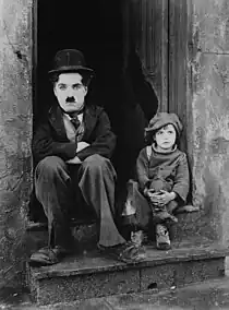 サイレント映画『キッド』(1921年公開)におけるチャールズ・チャップリンと子役ジャッキー・クーガンの有名なポートレート。チャップリンは放浪者をクーガンは孤児を演じており、この写真では他人の家の出入り口に二人して腰を下ろしている。クーガンはこの作品で子役の黎明期を代表するスターとなった。撮影時は5~6歳。子役としての活動期間は1917年から1933年まで。映画は1931年製まで、少なくとも22作品に出演した。