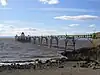 金属製の細い桟橋が海に向かって建ち、手前にはビーチがある