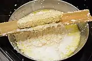 トウモロコシの穂軸からフライパンに粒をそぎ落とす。