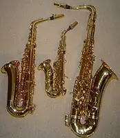 サクソフォーン族 – 左から右へ、E♭アルトサクソフォーン、湾曲型B♭ソプラノサクソフォーン、B♭テナーサクソフォーン