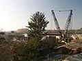 左側に一部完成した新しい橋、右側には地盤の沈下によって転覆した建設用クレーンと古い橋の基礎