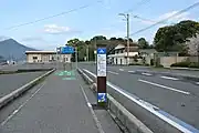 大三島・上浦町瀬戸。ブルーライン・矢羽・案内看板が設置されている。ここでは旧来からの歩道側の自転車道標示も残る。