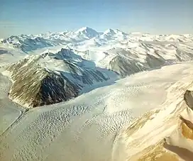 Aerial view: mountain ranges at top and bottom right of picture are separated by a broad ice river.
