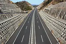 画像左 : 新東名として2012年に開通した静岡県区間の島田金谷IC付近。ICやSA等の分合流箇所では付加車線追加として当初から片側3車線で運用。画像右 : 岡崎SA付近。愛知県区間は用地は往復6車線で取得済みだが構造物は往復4車線仕様。このため静岡県区間と比べると幅員は狭い。