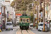 江ノ島 - 腰越間の併用軌道区間。道路の中央に軌道が通っている。電車前方右側には、遠方信号機が進行現示を出していることが覗えるが、この信号機は国道467号線歩道上に建植されている。