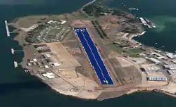 左右に建物が並ぶ島の光景、中央に滑走路をパネルで覆うコンセプト・デザインが画かれている。