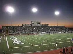A football stadium from the perspective of a fan in the stands. The touchdown area and yard markers can be seen. The seats on the other side of the stadium are in the background.