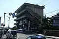 M.画像Lの交差点に出た様子。この交差点が県道22号の終点と県道47号の始点である。この付近の道路は広い為、多くの乗用車が海岸側に駐停車している。なお中央の建物は福山市役所鞆支所が入居している。