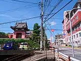 1874年の写真と同一方向から眺めた現在の悟真寺。戦後の道路拡張工事に伴い赤門は西側（山側、写真では左側）に移設された。