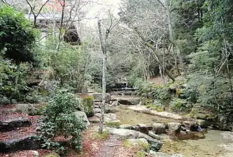 写真中央の路より左側が岩惣敷地。写真中央の石積より右側が紅葉谷川庭園砂防施設。