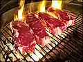 ステーキを炭火でグリル（網焼き）している。
