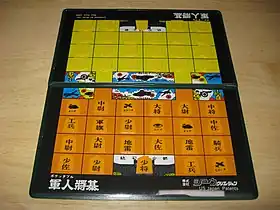 軍人将棋盤の一例。手前(オレンジ)は駒の種類がわかるように表向けに配置しているが、対局するときには奥(黄色)のように裏向けに配置する