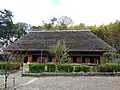 日本民家集落博物館に移設された日向椎葉の並列型民家（重要文化財）の外観。屋根は茅葺の寄棟に置き千木。