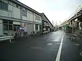 南武線と鶴見線の駅間の道路。右の地上駅舎が南武線のもので、線路は右方向に伸びて行く。中央奥の階段が鶴見線の駅の入り口で、線路は道路と平行に伸びている。右上の高架はかつて塩浜操車場と安善駅方面を直接結んでいた貨物線で、廃止後もこのように放置されている。(2006年12月)