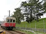東鳴尾駅付近を走る7861形電車。右側は武庫川の堤防と松の木。（2013年）